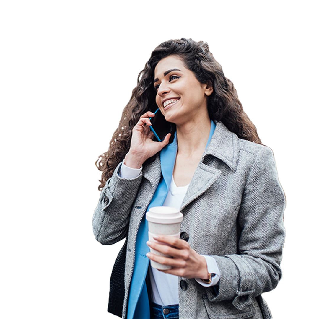 Women with curly hair in gray coat smiling while talking on the phone